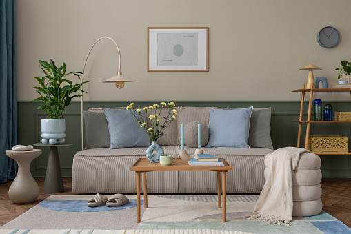 Modern living room with a beige sofa, sage green wall panels, geometric area rug, and potted plants
